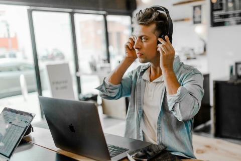 Image of a man at a desk with a laptop & headphones